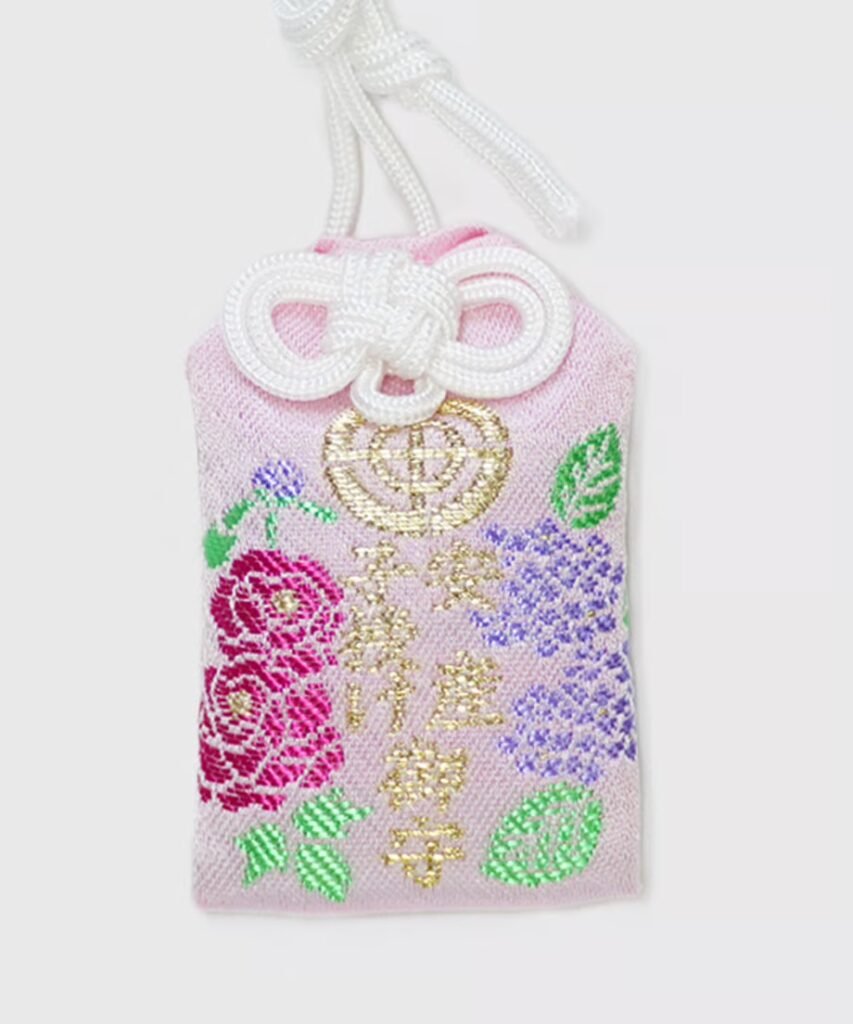 Pink floral omamori embroidered with bright pink roses, purple and green flowers, and gold Japanese characters